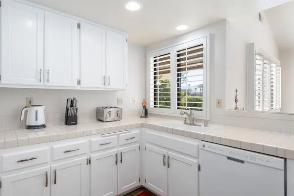 a kitchen with white cabinets and window