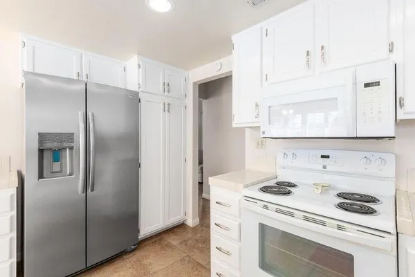 a kitchen with a refrigerator stove and white cabinets