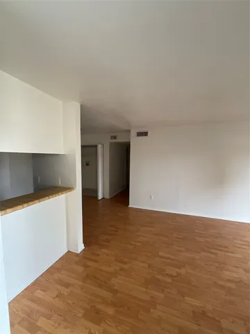 a view of an empty room with kitchen and a window