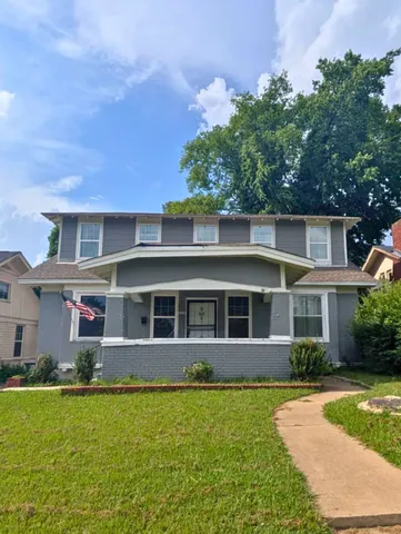 a front view of a house with a yard and potted plants