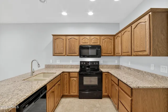 a kitchen with granite countertop a sink dishwasher stove and oven with cabinets