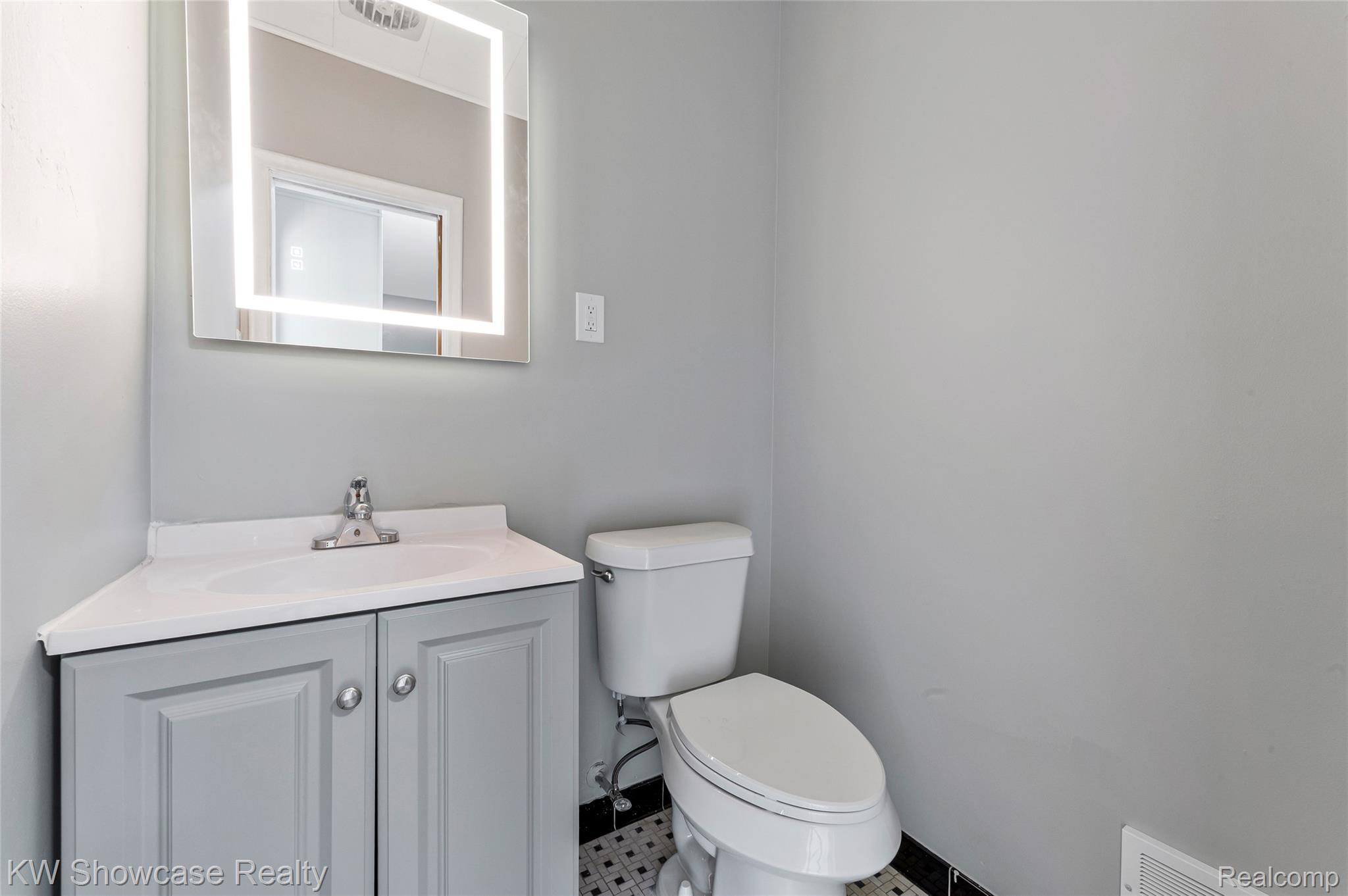 8936 Merriman Road Livonia, MI 48150 - Photo 36 of 49 Modern corner vanity with light grey cabinetry, integrated sink, and an illuminated mirror