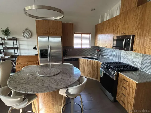 a kitchen with granite countertop a stove a sink and a refrigerator