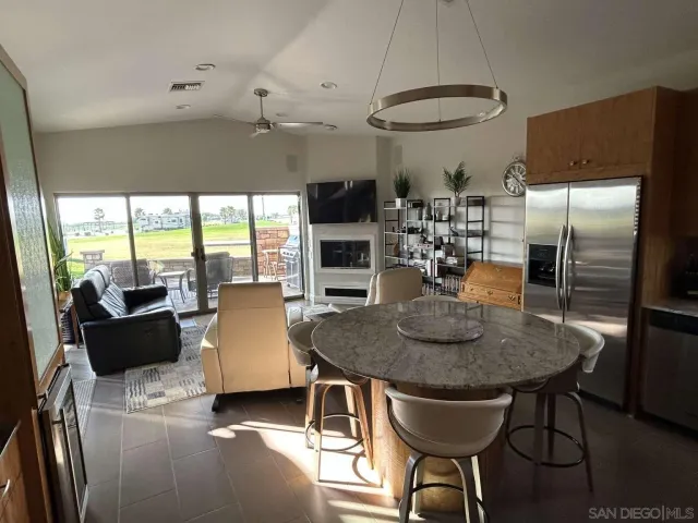 a kitchen with stainless steel appliances granite countertop a table chairs and a refrigerator