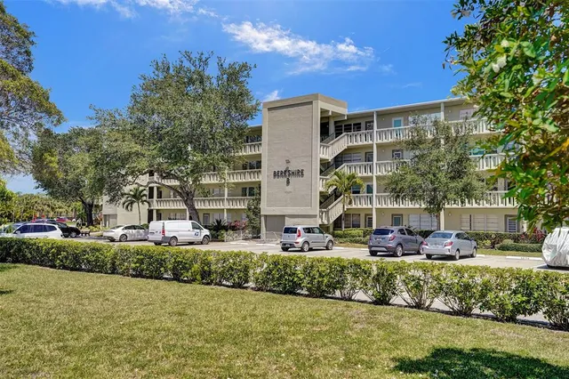 a front view of a building with garden and trees