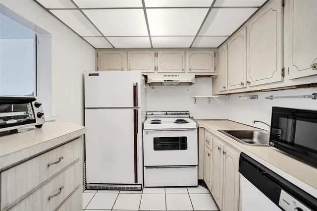 a kitchen with stainless steel appliances granite countertop a refrigerator a stove a sink and white cabinets