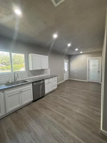 a large kitchen with stainless steel appliances granite countertop a large counter top a sink and a dishwasher