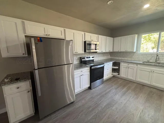 a kitchen with a refrigerator a sink dishwasher and a stove top oven