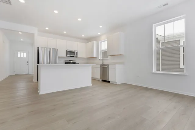 a view of kitchen with kitchen island white cabinets and refrigerator