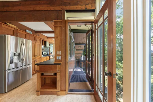 a view of a hallway with wooden floor and a kitchen