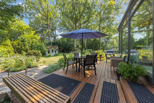 a view of a patio with table and chairs under an umbrella with wooden floor and fence
