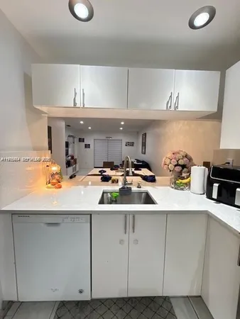 a kitchen with a refrigerator sink and white cabinets