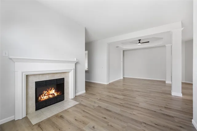 a view of an empty room with wooden floor fireplace and a window