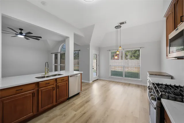 a kitchen with stainless steel appliances granite countertop a stove a sink dishwasher and a refrigerator with wooden floor