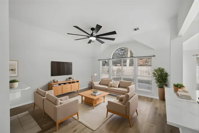 a living room with furniture a ceiling fan a flat screen tv and a window