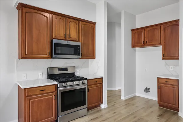 a kitchen with granite countertop wooden cabinets and a stove top oven