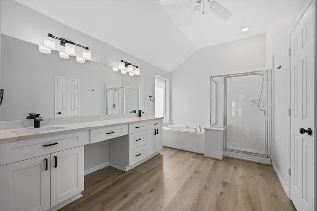 a large white kitchen with a sink dishwasher a stove and white cabinets with wooden floor