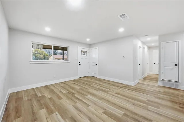 a view of empty room with wooden floor and window
