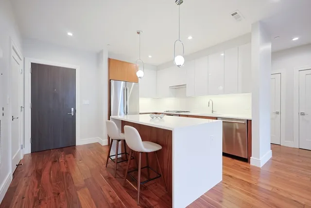 a kitchen with kitchen island wooden floors and stainless steel appliances