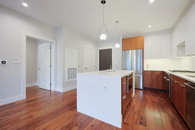 a kitchen with stainless steel appliances granite countertop a refrigerator a sink and wooden floor