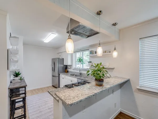 a kitchen with stainless steel appliances granite countertop a sink a stove and wooden cabinets