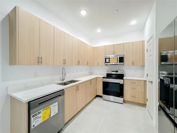 a kitchen with stainless steel appliances granite countertop a refrigerator a stove a sink and a microwave