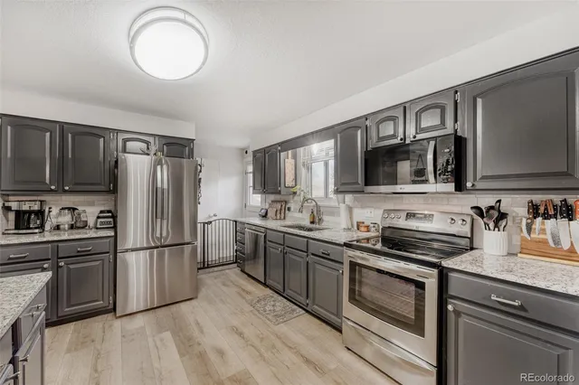 a kitchen with stainless steel appliances granite countertop a refrigerator stove top oven and sink