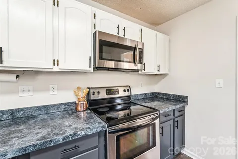 a kitchen with stainless steel appliances granite countertop white cabinets and a stove top oven