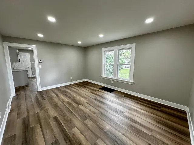 an empty room with wooden floor and a window