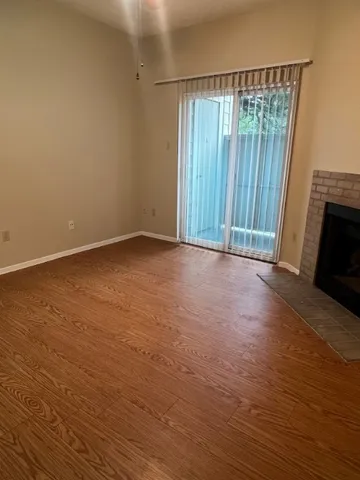 an empty room with wooden floor fireplace and windows