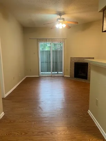 a view of an empty room with glass door and wooden floor