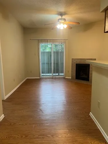 a view of an empty room with glass door and wooden floor