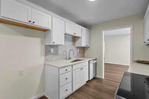 a view of kitchen with wooden floors and white cabinets