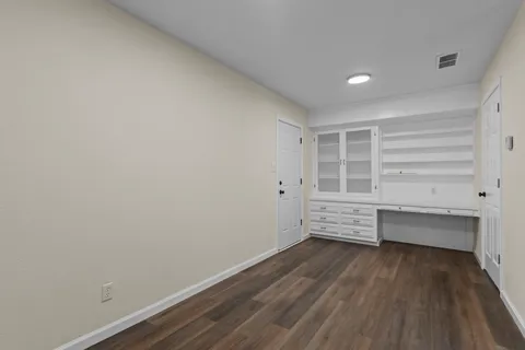 a view of an empty room with wooden floor fireplace and a window