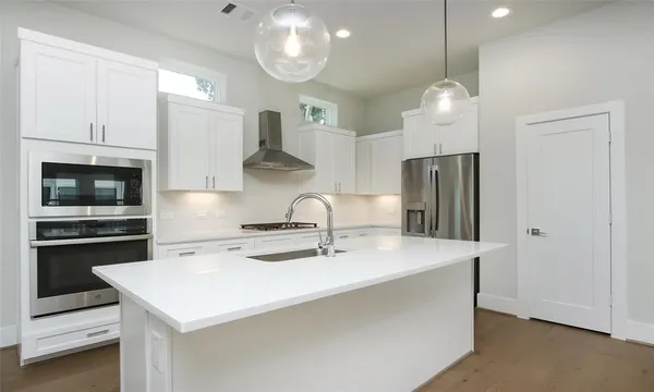 a kitchen with stainless steel appliances a table a refrigerator and a stove top oven