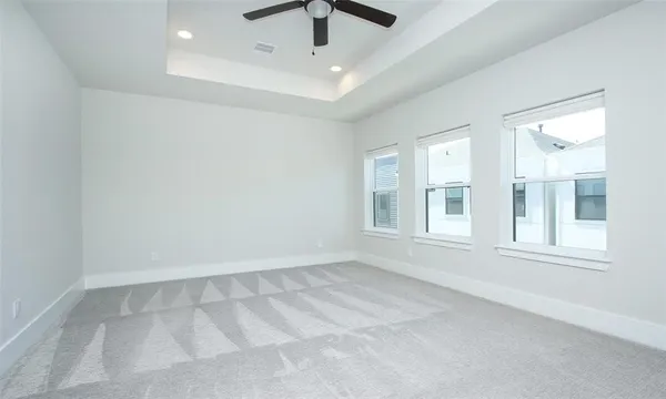 an empty room with chandelier fan and windows