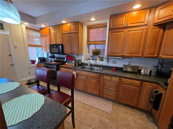 a kitchen with stainless steel appliances granite countertop a sink dishwasher a refrigerator and a chair with the view of living room