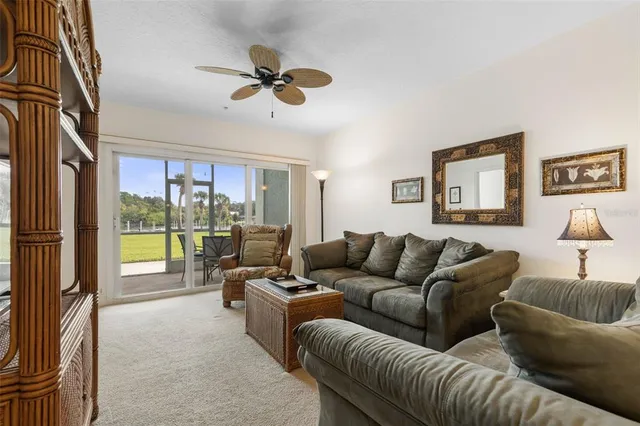 a living room with furniture ceiling fan and a large window