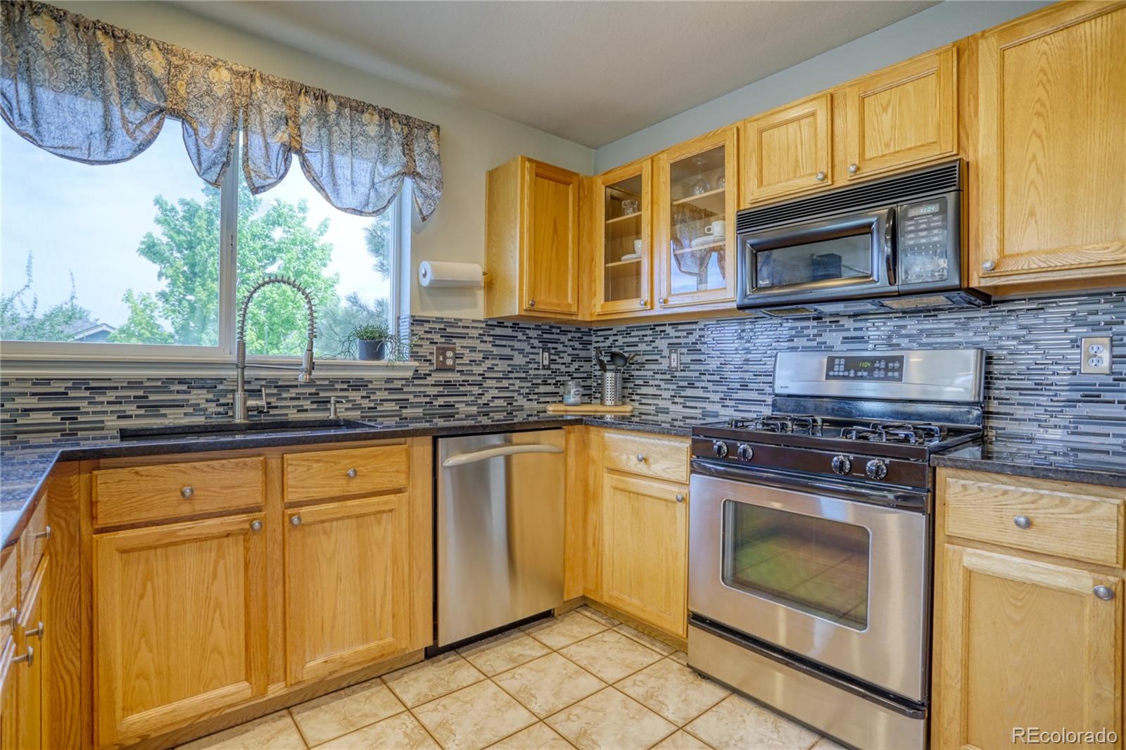 659 Timbervale Trail Highlands Ranch, CO 80129 - Photo 7 of 32 a kitchen with stainless steel appliances a stove sink and cabinets