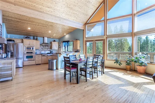 a view of a dining room and livingroom with furniture wooden floor and a large window