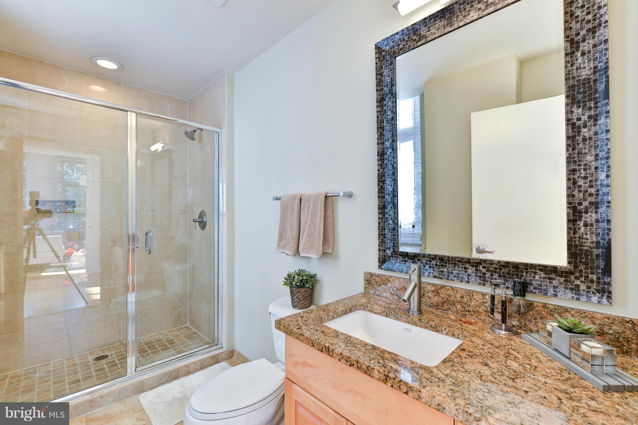 811 4th Street Northwest, Unit 218 Washington, DC 20001 - Photo 23 of 28 a bathroom with a granite countertop sink toilet mirror and shower