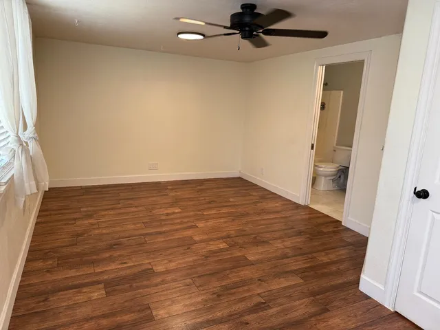 an empty room with wooden floor and a ceiling fan