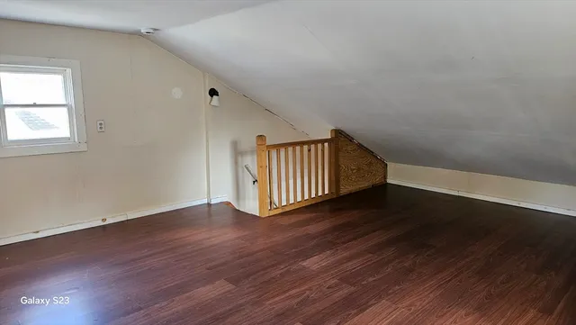 a view of an empty room with wooden floor and windows