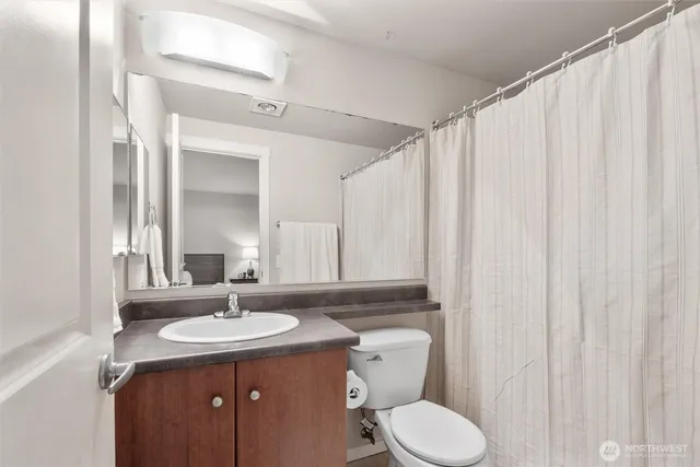 a bathroom with a granite countertop sink toilet and mirror
