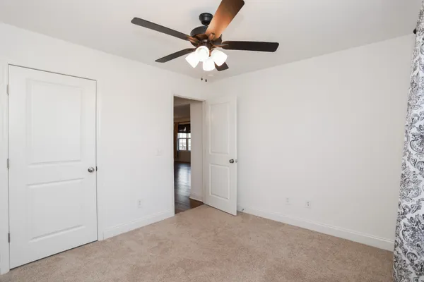 an empty room with closet and a chandelier fan