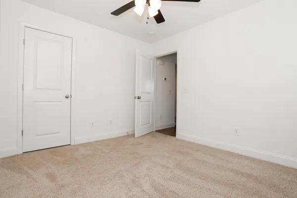 an empty room with a ceiling fan and carpet