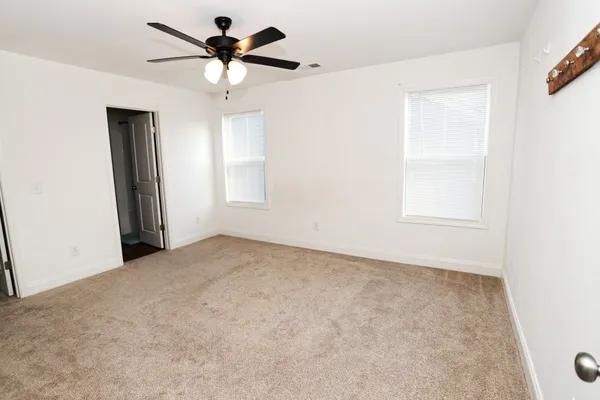 an empty room with windows and fan