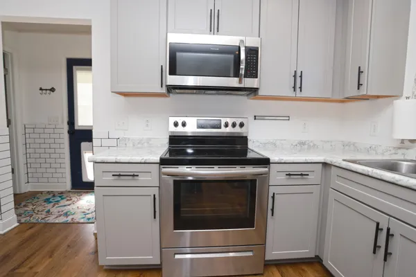 a kitchen with granite countertop white cabinets and white appliances