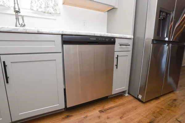 a view of a refrigerator in kitchen and an empty room