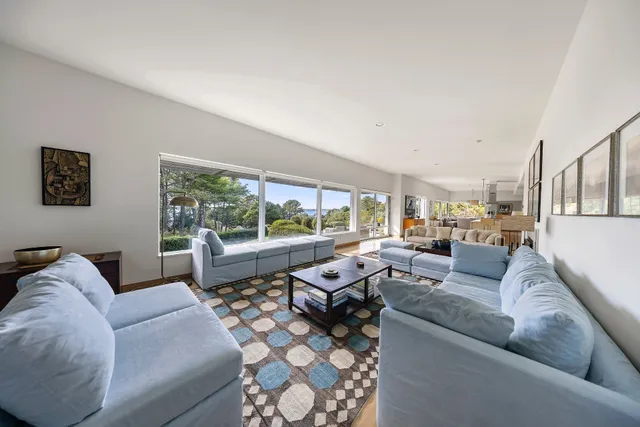 a living room with furniture large window and a table